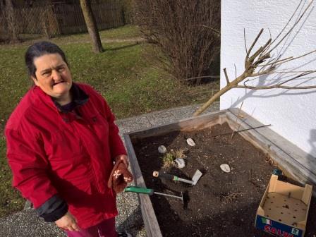 Sie sehen eine Frau mit Behinderung bei der Gartenarbeit