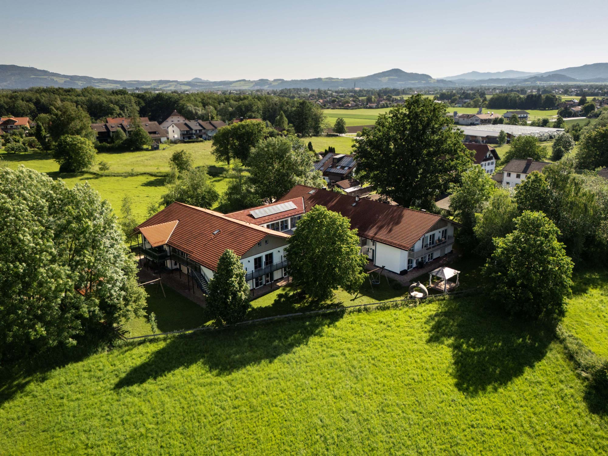 Das Wohnhaus Adelstetten auf einer Lustaufnahme. Rund um das Haus sind viele grüne Felder und Wälder.