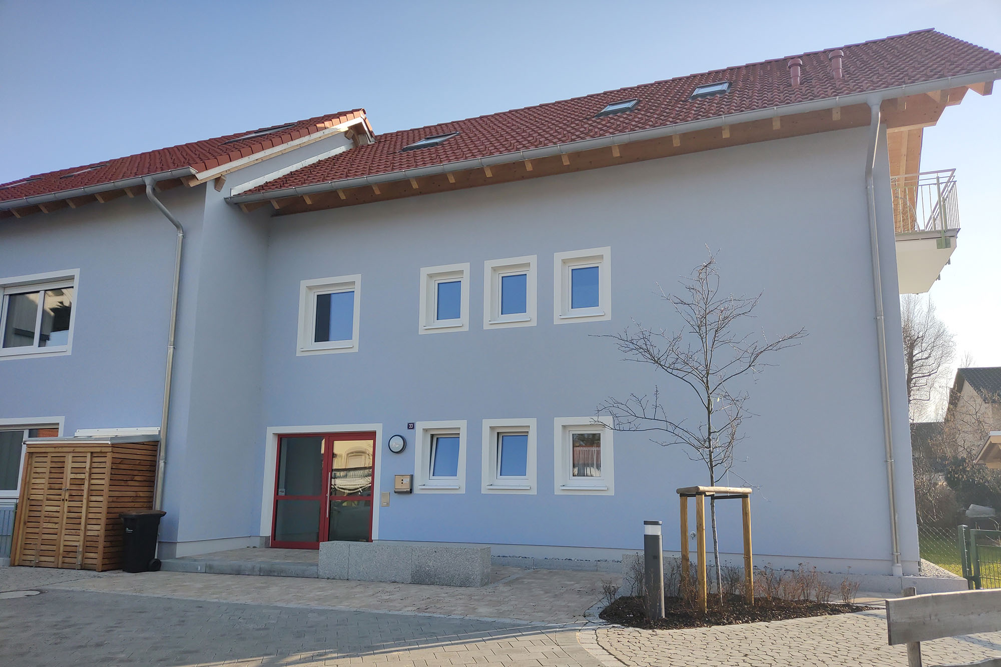 Der Eingangsbereich der inklusiven WG: eine helle, freundliche Fassade und eine rote Eingangstür.