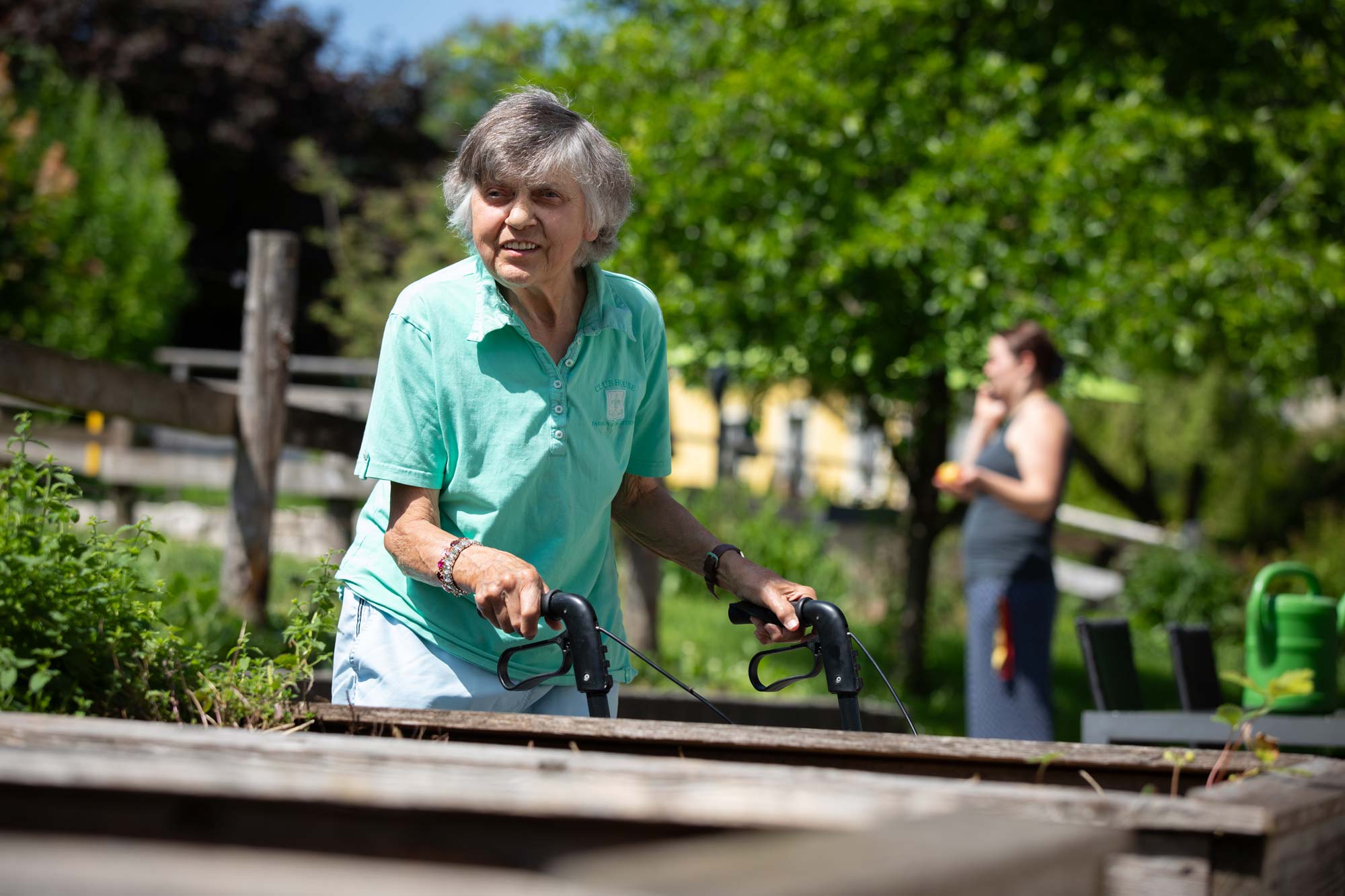 Eine Seniorin mit Rollator genießt den Garten.